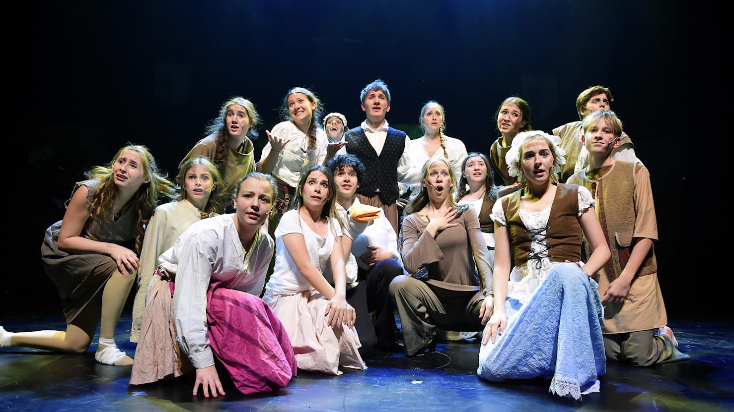 Theateraufführung mit vielen Darstellern auf der Bühne.