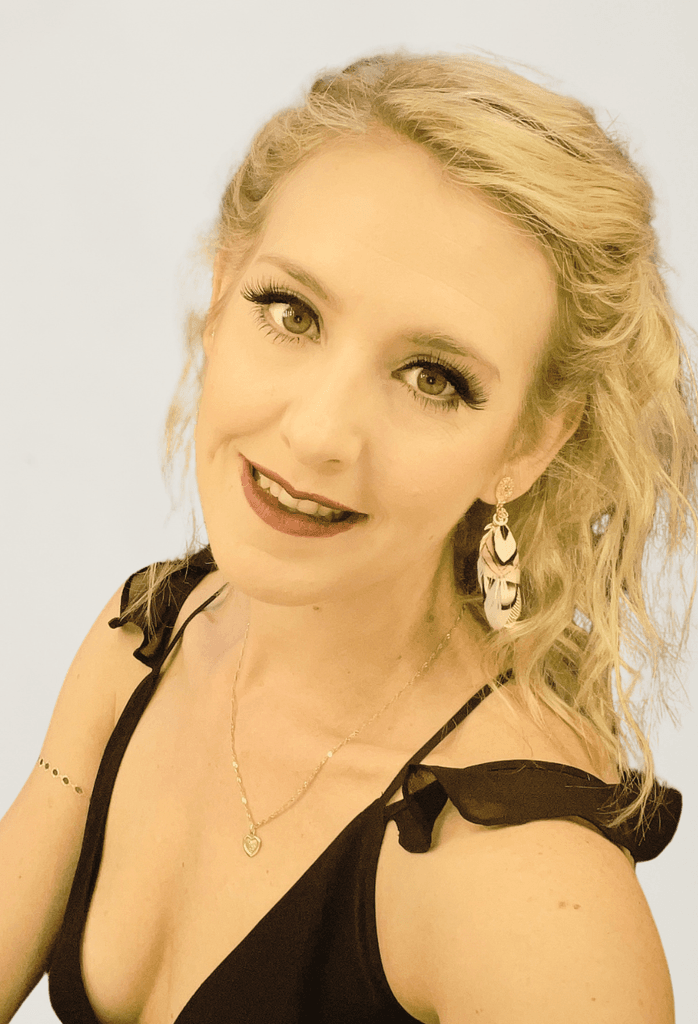 Frau mit blonden Locken und Ohrringen lächelt.